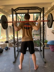 Jordan fernandez showing the barbell back squat top position for bjj workouts