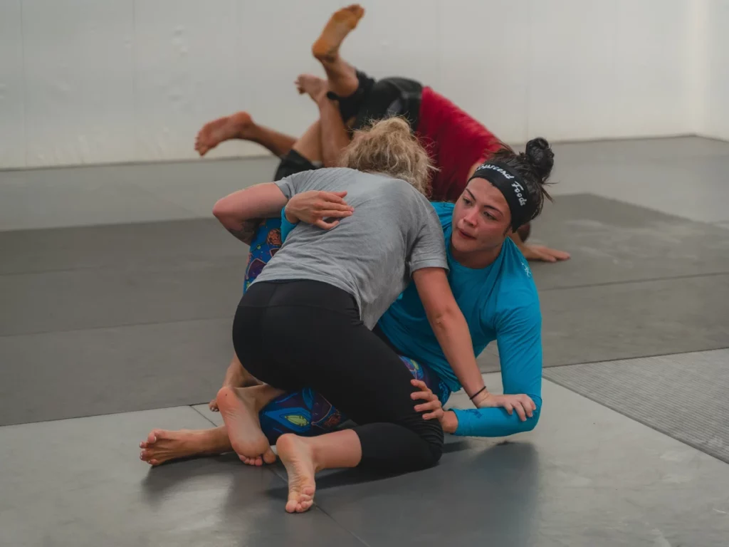two women grappling in BJJ with underhook, guard passing from half guard